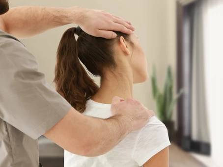 a6bca24f25434fd5a3eafeb13bb32b57 a physio therapist treating a female patient. His hands are on her neck, bending it slightly to the left side.