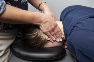 Physio treating neck of patient lying face down Headache Neck and Jaw Clinic