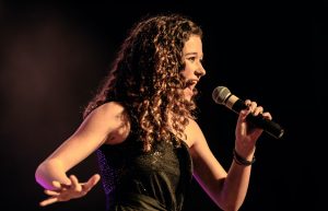 Lady singing into microphone on stage