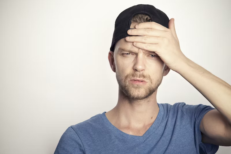 Man with concussion holding his forehead.