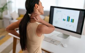 Lady facing computer holding sore neck.jpg