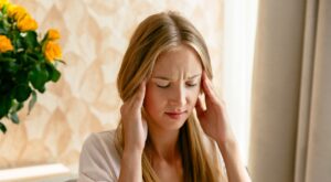 Young woman suffering from migraine holding her head