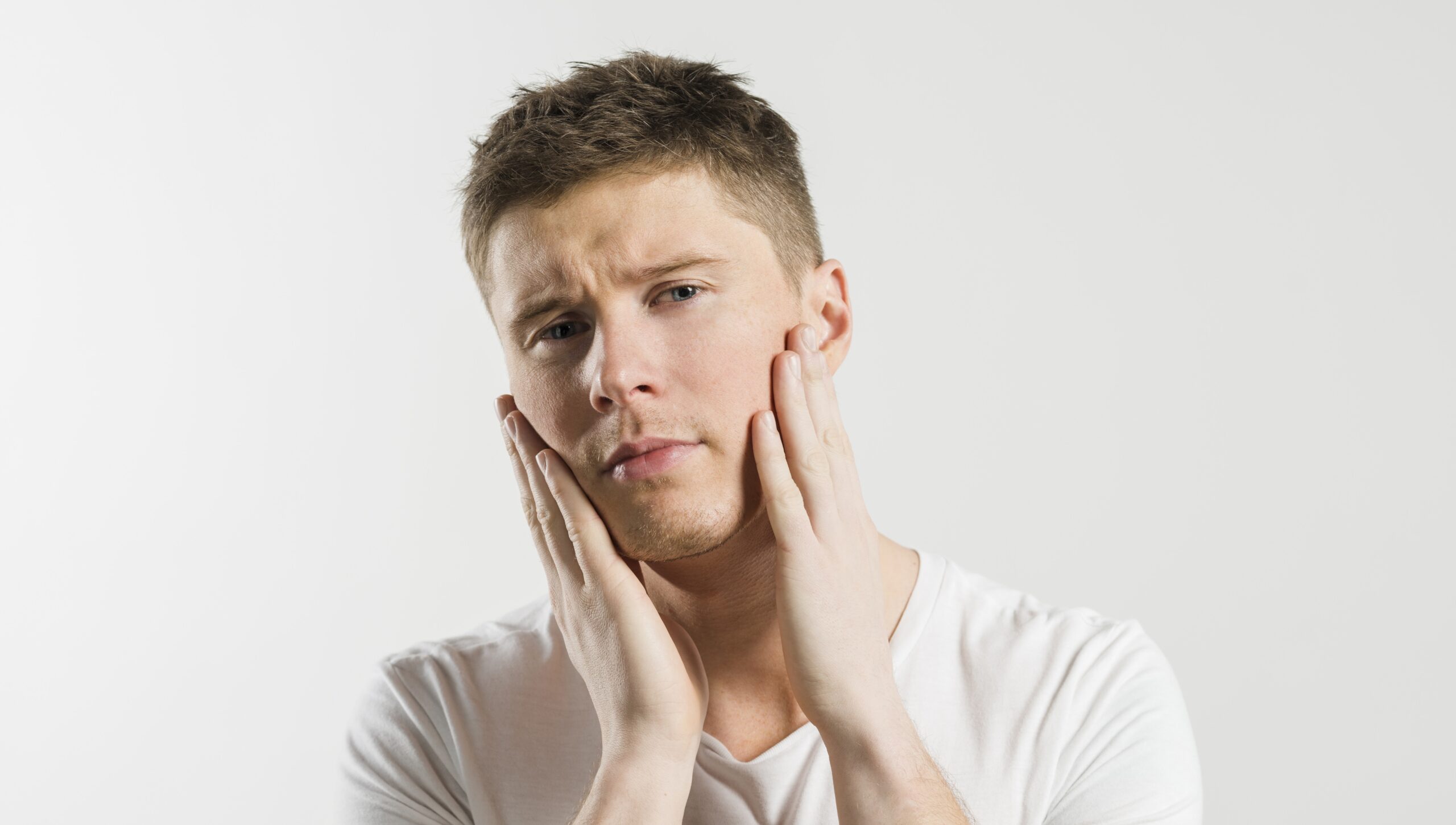 Young man holding sore jaw
