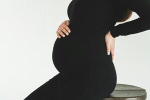 Pregnant lady in black holding her belle and back
