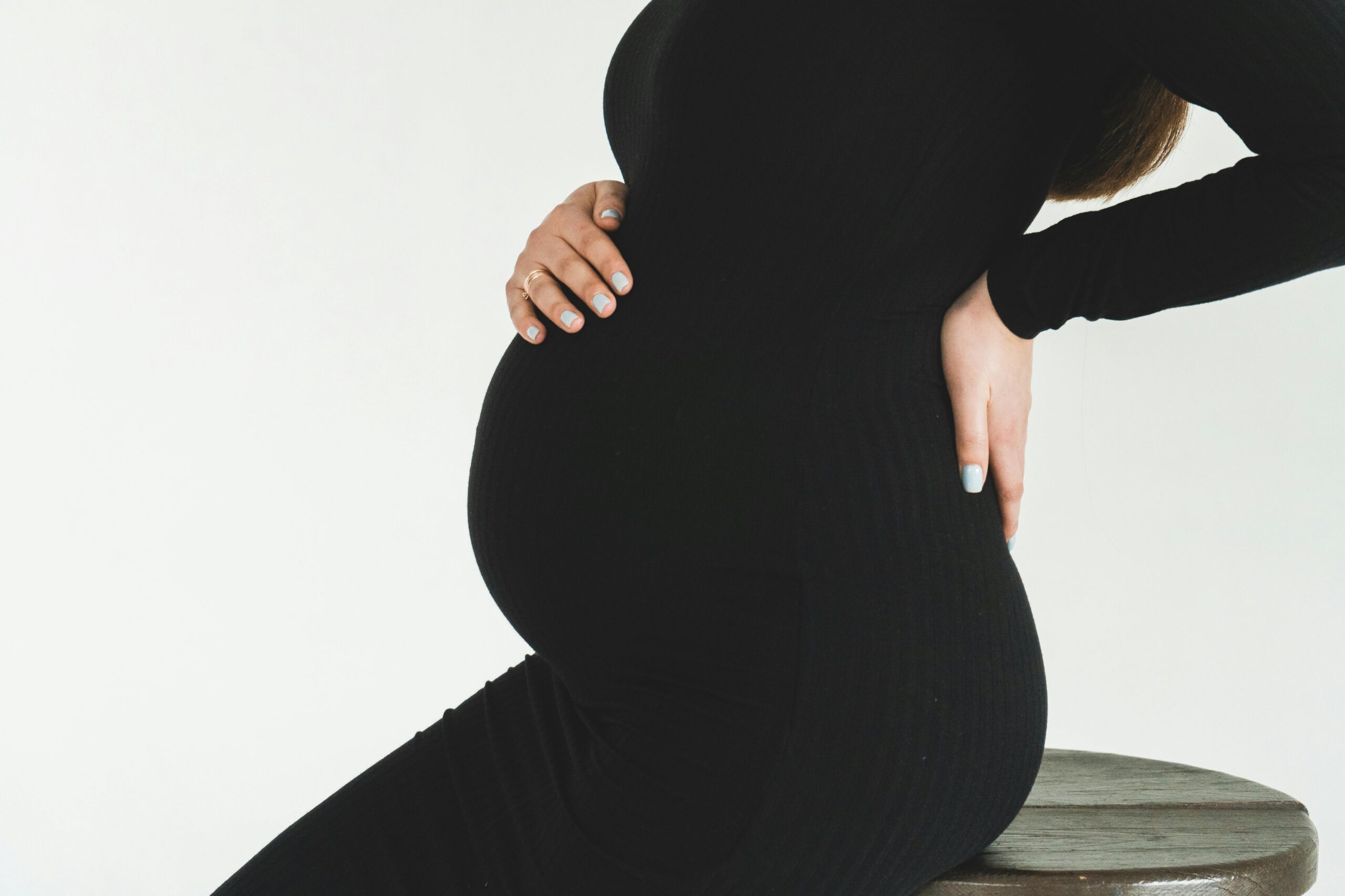 Pregnant lady in black holding her belle and back