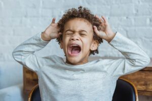 Boy sitting at desk holding his head